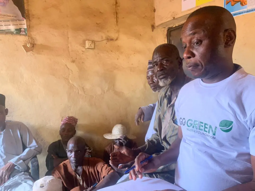 A Go Green Nigeria Foundation team member seated with community elders