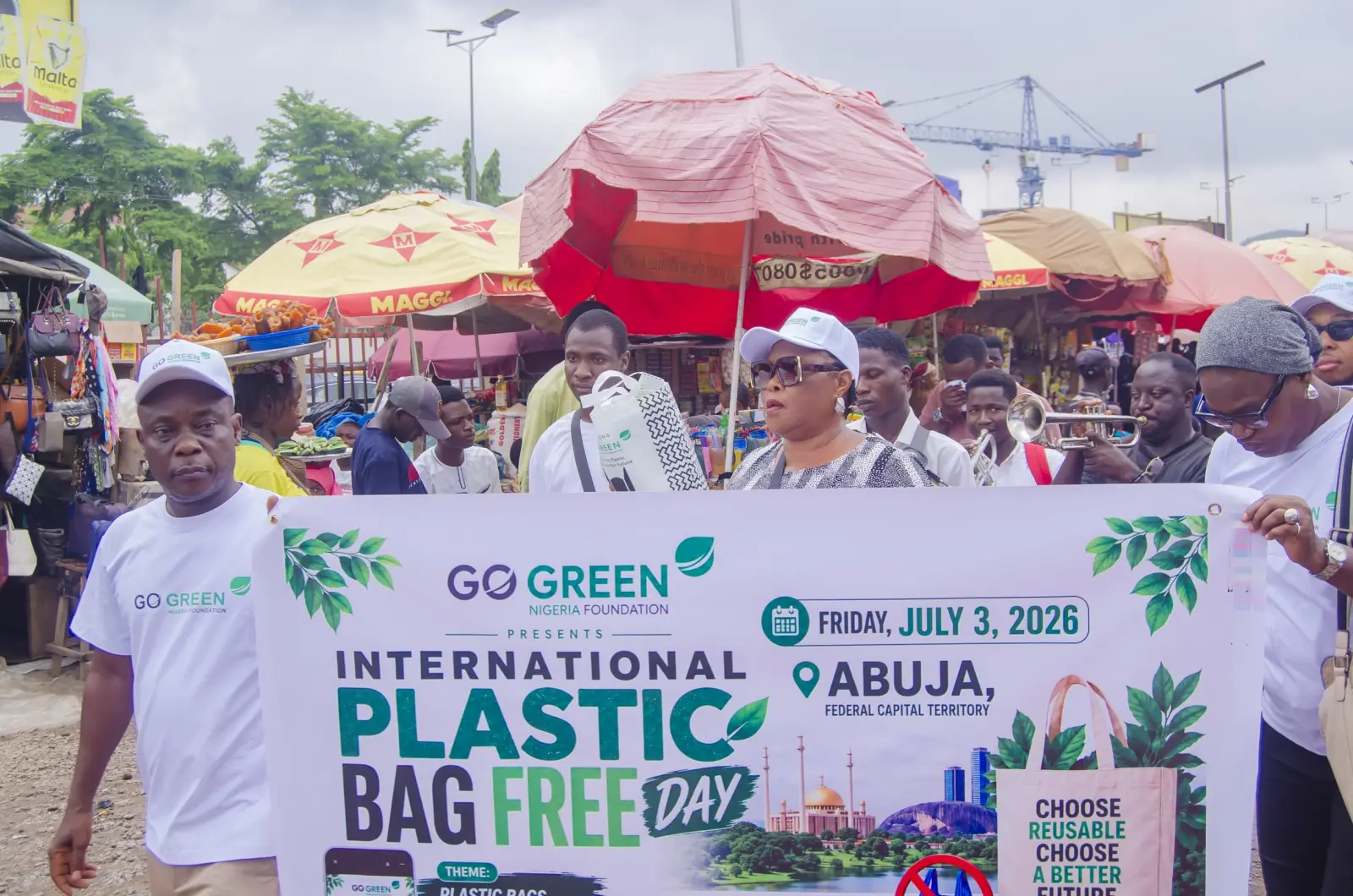 Volunteers holding an International Plastic Bag Free Day banner at a market in Abuja